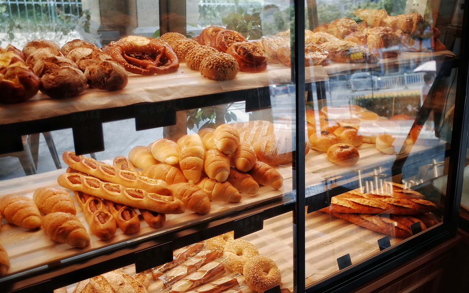 Shelves of fresh bread rolls, baguettes and croissants in a bakery display case